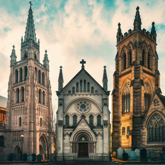 pittsburgh churches A picturesque, cinematic scene showcasing three of Pittsburgh’s most historic churches side by side: the grand Gothic spires of St. Paul Cathedral rising above a city skyline, the ornate façade of St. Anthony’s Chapel nestled in the Troy Hill neighborhood with hints of its vast relic collection inside, and the sandstone Gothic exterior of Trinity Cathedral downtown, surrounded by historic gravestones. The sky is bright with soft golden-hour lighting, illuminating the stained glass windows. The overall tone is warm, reverent, and timeless—celebrating Pittsburgh’s architectural and cultural heritage.