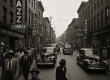 A black-and-white photograph of Pittsburgh’s Hill District in the 1940s – a busy Wylie Avenue filled with people, neon jazz club signs, and vintage cars – capturing the neighborhood’s vibrant “Little Harlem” era