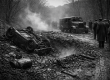 Vintage black and white scene of a cratered muddy road after a 1927 explosion in Western Pennsylvania, with an overturned escort car, a damaged armored truck, and men in coats and caps watching from a distance.